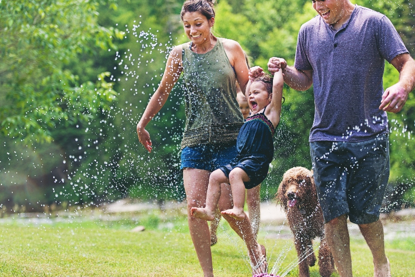 Family enjoying summer fun together with a sprinkler.