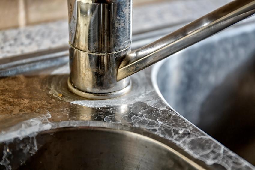 Hard water stains on a kitchen sink. Identifying and fixing these issues is a common water softener FAQ.