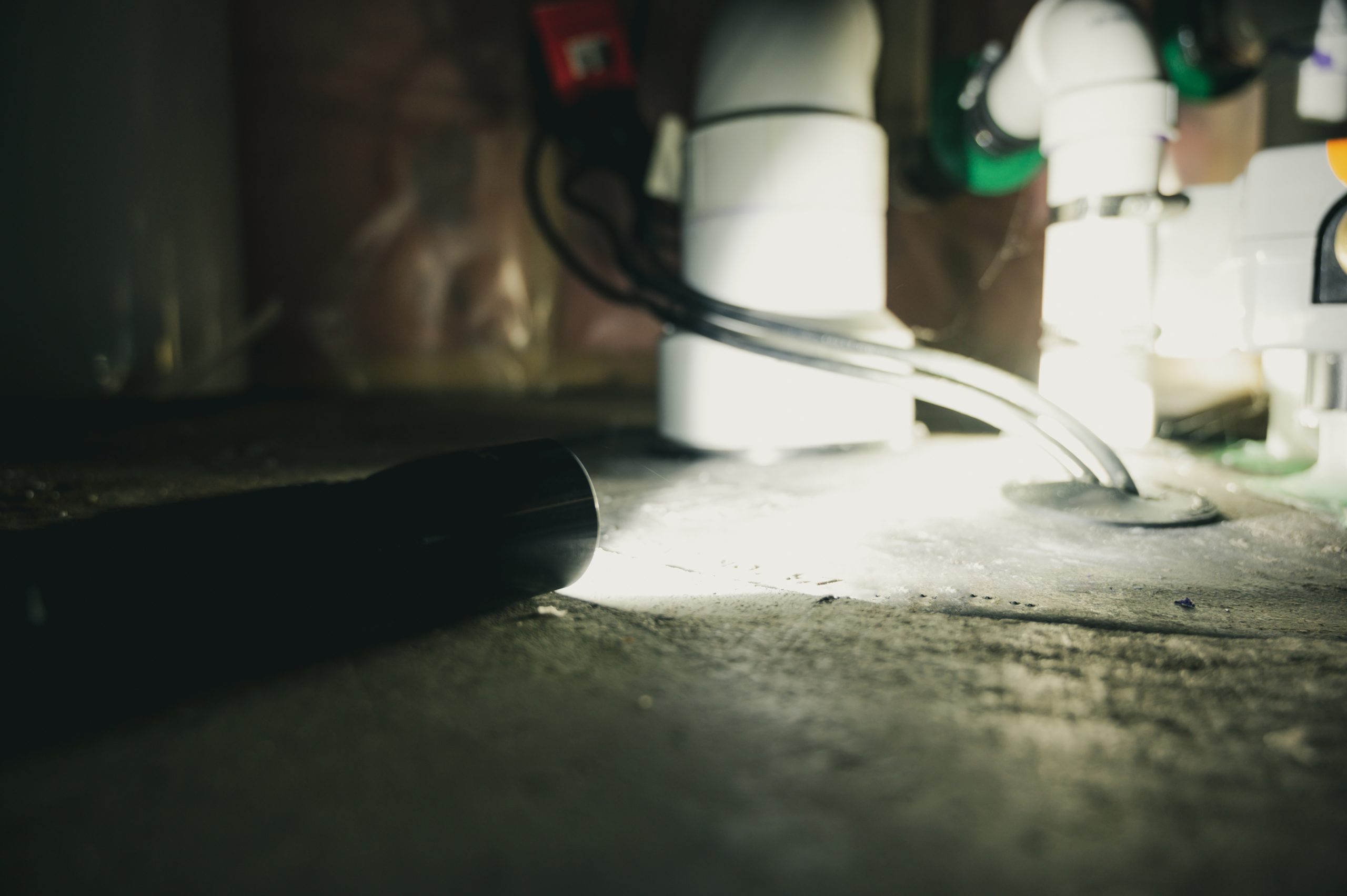 A flashlight illuminates a sump pump for maintenance.